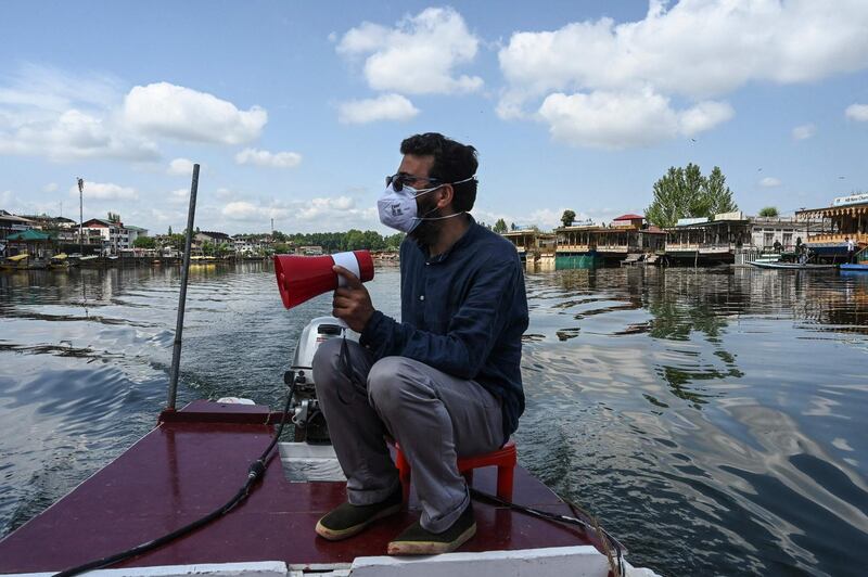 A man on a private ambulance boat announces Covid-19 protocols at Dal lake in Srinagar. AFP