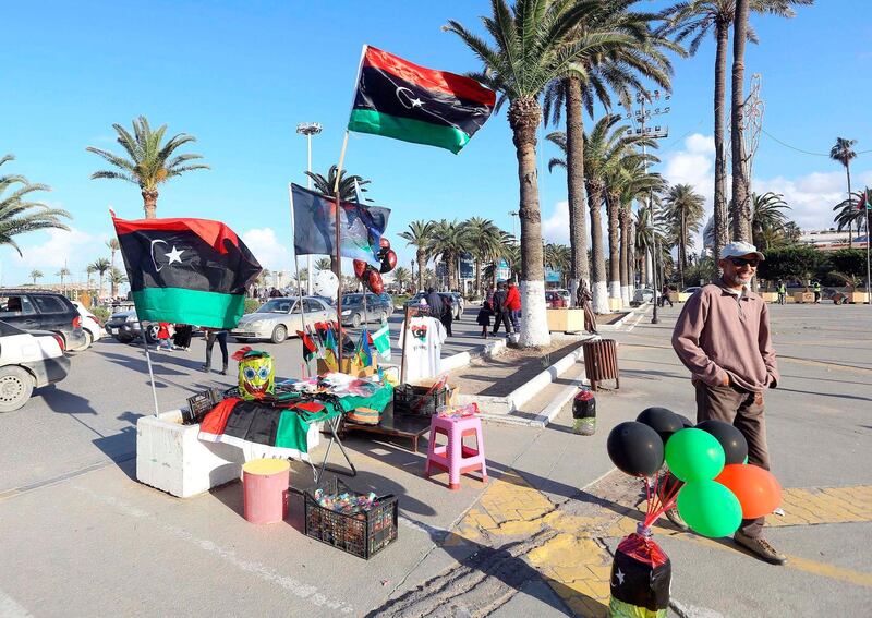 A vendor stands next to products he is selling, including the national flag, ahead of the eighth anniversary of the Libyan revolution which toppled late leader and strongman Moamer Kadhafi, in the capital Tripoli. AFP