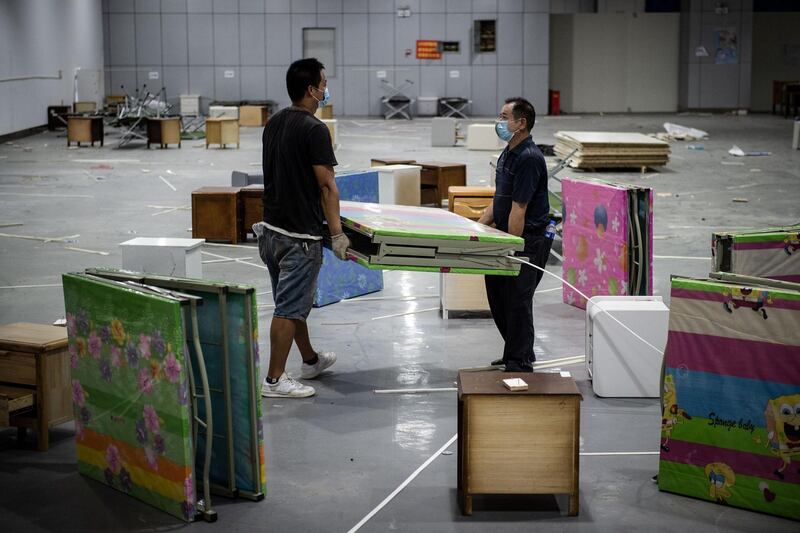 Workers move beds as they demolish installations at Wuhan's first makeshift hospital built to treat patients infected by Covid-19 in China's central Hubei province. AFP