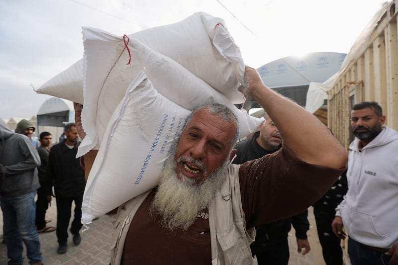 A Palestinian man carries flour bags distributed by UNRWA. Reuters