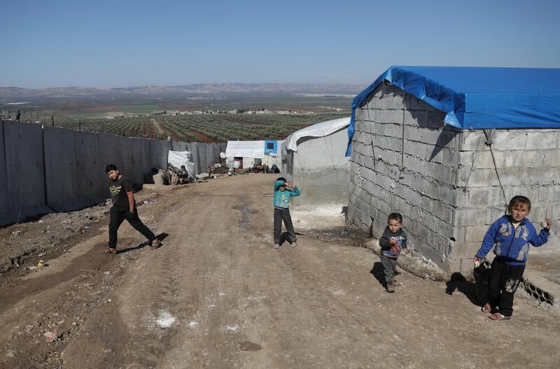 Internally displaced Syrian children walk near the wall in Atmah IDP camp, located near the border with Turkey, in Syria. Reuters