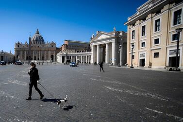 A woman wearing a face mask walks her dog along the border between Italy and The Vatican during the lockdown following the coronavirus pandemic. AFP / Filippo MONTEFORTE