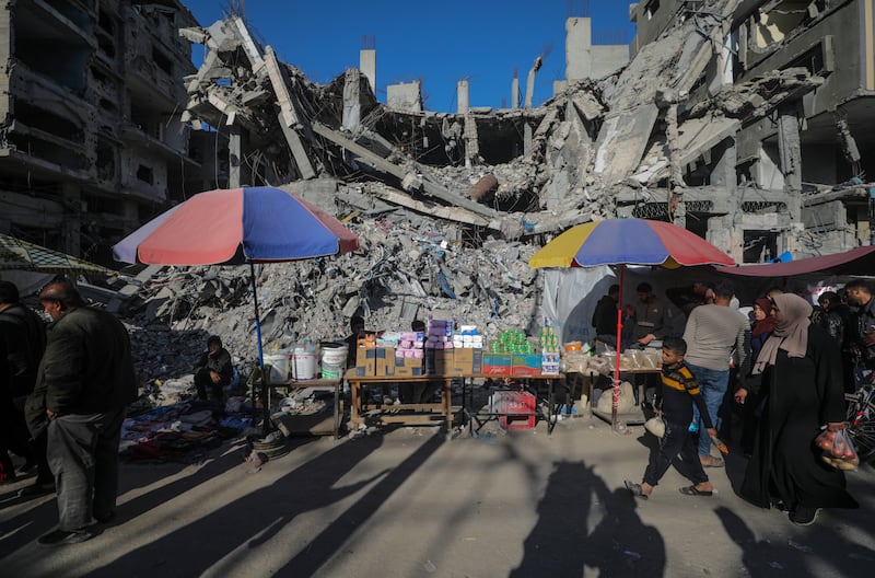 Palestinians walk past kiosks set up next to destroyed buildings in Al Nusairat refugee camp, the Gaza Strip EPA