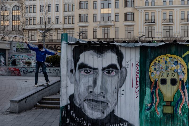 A skateboarder performs a trick behind a mural of poet and activist Vasyl Stus, in Kiev. Getty Images