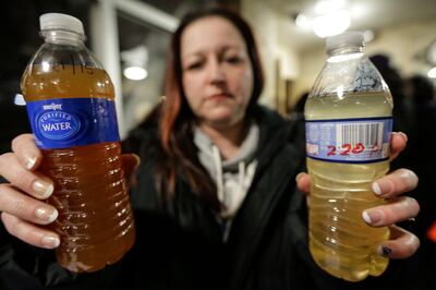 LeeAnne Walters of Flint, Michigan, shows water samples from her home from January 21, 2015 and January 15, 2015 after city and state officials spoke during a forum discussing growing health concerns being raised by Flint residents at the Flint City Hall dome. Detroit Free Press via AP