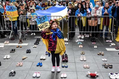 A child holds a sign while standing around a collection of shoes placed to represent killed Ukrainian children during a rally in support of Ukraine, on March 26, in New York City. Getty / AFP
