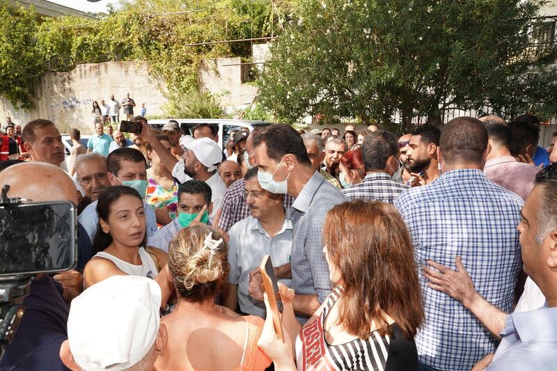 President Bashar Al Assad surrounded by locals of Mashta Al Helou village in central Syria, where he is inspecting the damage caused by the wildfire that hit three Syrian provinces few days ago.  EPA