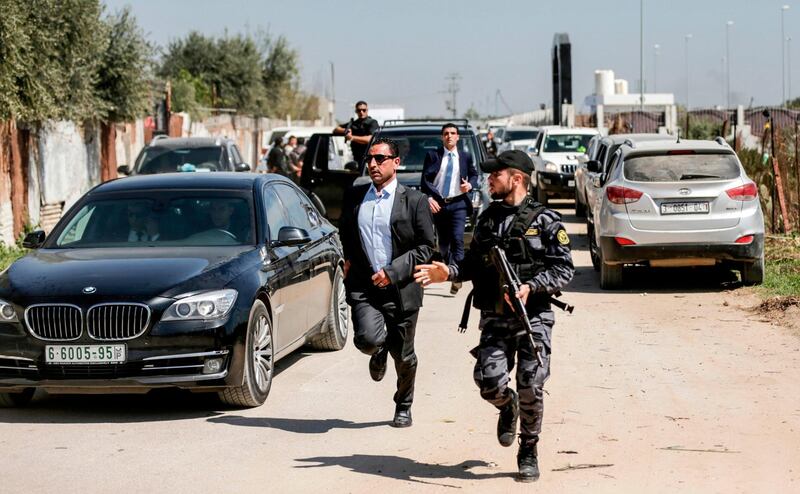 A bodyguard of the Palestinian Prime Minister (centre) and a Hamas security officer (right) escort the PM's convoy as he leaves Gaza City on March 13, 2018. Mahmud Hams / AFP