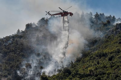 A helicopter drops water onto a forest fire near Malakasa, north of Athens.  (Photo by Louisa GOULIAMAKI  /  AFP)