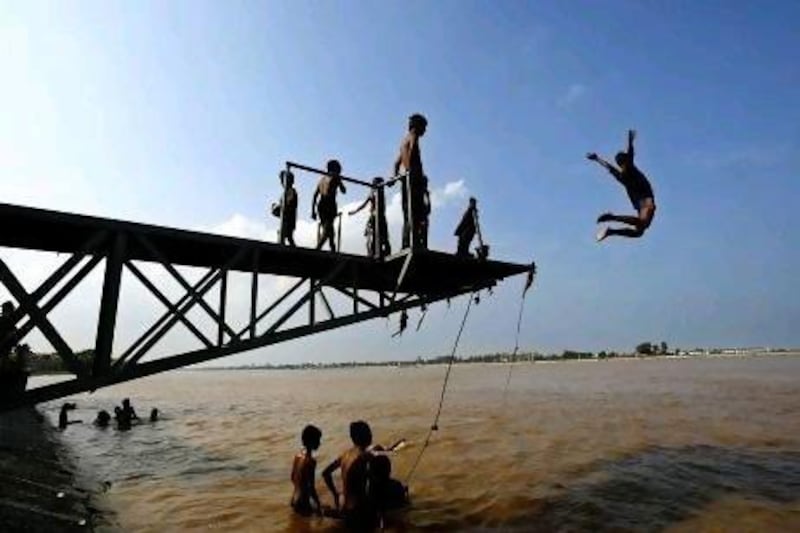 Cambodian children jump off a platform into the Tonle Sap river where it meets the Mekong River in Phnom Penh, Cambodia. AP Photo/Andy Eames
