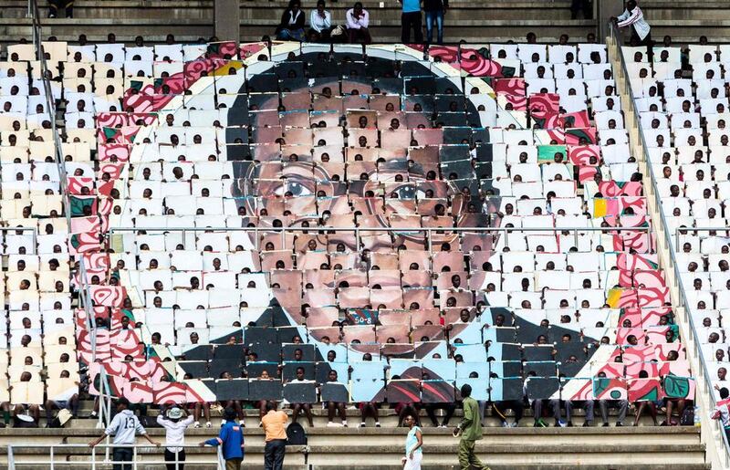 School children hold an image of Zimbabwe’s president Robert Mugabe during the country’s 37th Independence Day celebrations at the National Sports Stadium in Harare. AFP