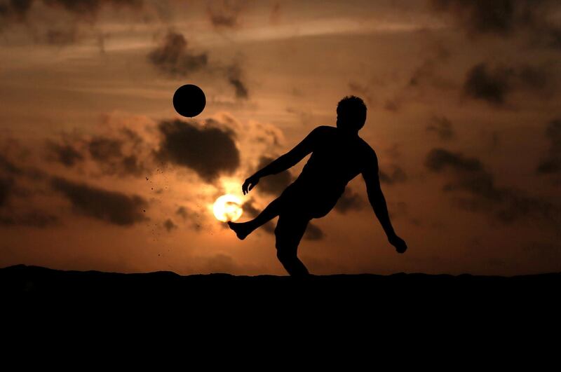 A boy is silhouetted against the sunset as he plays with a soccer ball in Colombo, Sri Lanka. Reuters