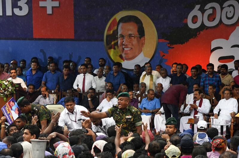 Sri Lankan police officer tries to control supporters of Sri Lanka's former president and newly appointed prime minister Mahinda Rajapakse and President Maithripala Sirisena at a rally in Colombo on November 5, 2018. Thousands of supporters of former Sri Lankan president Mahinda Rajapakse headed for the capital on November 5 to rally in support of his controversial nomination as prime minister, as the island's constitutional crisis deepened.
 / AFP / LAKRUWAN WANNIARACHCHI
