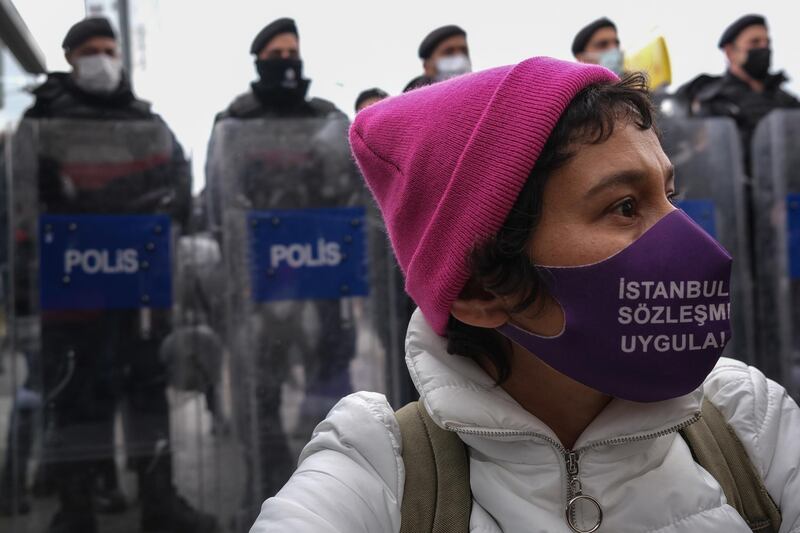 A protester wears a face mask written  'Apply Istanbul Convention' as she shouts slogans while Turkish riot police block the way during a protest against Turkey's decision to withdraw from the Istanbul Convention on March 31, 2021. EPA