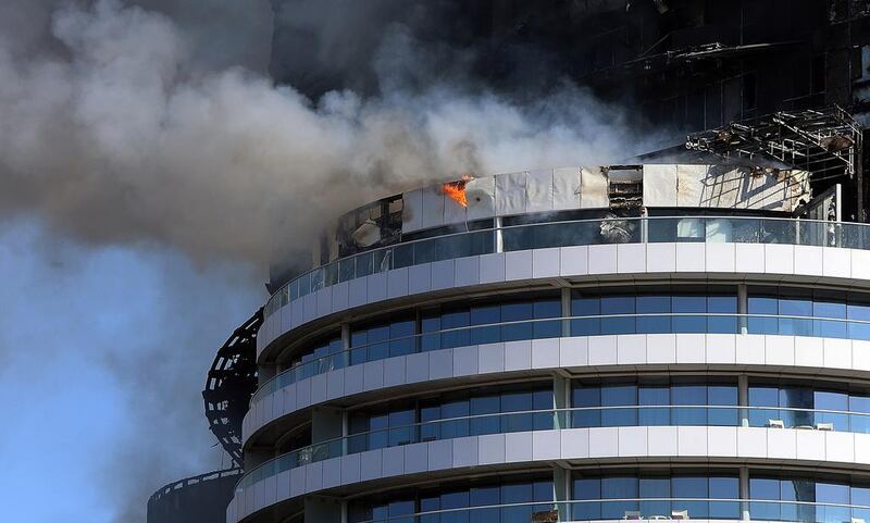 Fresh flames coursed through the glass facade and large chunks of debris fell as the fire spread along the building’s rim, near sections that were charred in the blaze that began around 9.30pm on Thursday. Satish Kumar / The National