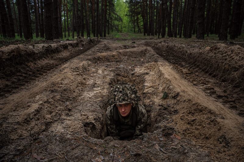A Ukrainian soldier lies in a trench during a military exercise in the Kharkiv region. AFP
