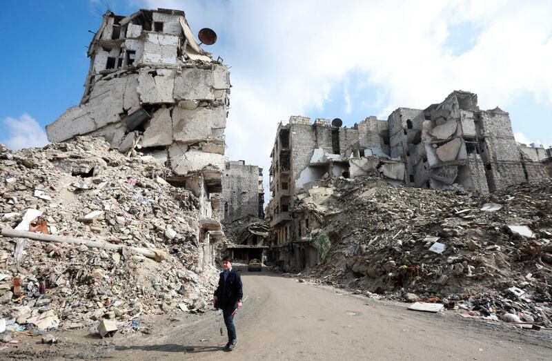 TOPSHOT - People walk past the rubble of buildings that were heavily damaged or destroyed during battles between rebel fighters and regime forces, in the former opposition-held district of Salaheddin in the northern Syrian city of Aleppo on February 11, 2019,  three years after the Syrian regime regained, with Russian firepower help, rebel-held territory and took full control of the country's second city. / AFP / LOUAI BESHARA

