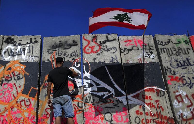 A Lebanese activist paints graffiti on a concrete wall installed by authorities a day before near the main government building in downtown Beirut on August 25, 2015. Shortly after, the wall was taken down on orders from the prime minister, likely as a move to appease demonstrators who dubbed it a "wall of shame". Hassan Ammar/AP Photo