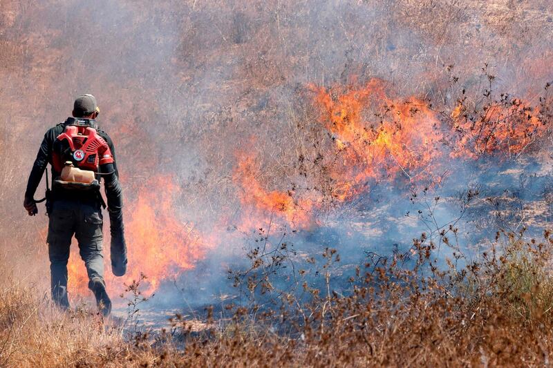 An Israeli worker from the Nature and Parks Authority tries to extinguish a fire caused by an incendiary balloon launched from the Gaza Strip, near Beeri Kibbutz.  AFP