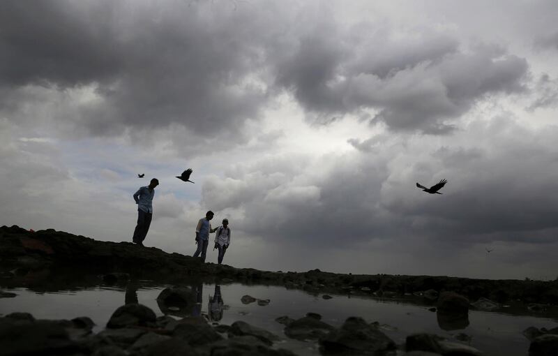 A plainclothes police man center, requests people to move away from the shores of the Arabian Sea as monsoon clouds fill the sky in Mumbai, India, Wednesday, June 12, 2019. Indian authorities were bracing Wednesday for a severe cyclone gathering strength in the Arabian Sea that was expected to make landfall in the western state of Gujarat as India's second major storm of the season. In India's financial capital of Mumbai, police tweeted that because of the high winds, heavy rainfall and lightning expected from Vayu, people "should not venture into sea and should keep safe distance from shoreline." (AP Photo/Rafiq Maqbool)