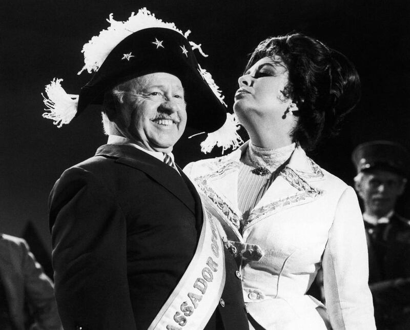 In August 27, 1981, veteran comic Mickey Rooney wears a Napoleonic-era hat as he tapes an I love New York television commercial with British-American actress Elizabeth Taylor, in New York. AP Photo / GPB, File