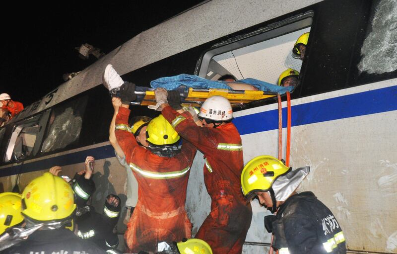 Firefighters rescue an injured survivor from the wreckage of a high-speed train which derailed between the cities of Hangzhou and Wenzhou, in eastern China's Zhejiang province on July 23, 2011.  Emergency workers battled to rescue survivors from the mangled wreckage of the two Chinese bullet trains involved in a high-speed collision which left 33 dead and nearly 200 injured, reports said. The first train had been halted by a lightning strike and was rear-ended by the second, state media said, causing two carriages to fall off a viaduct in a disaster likely to raise fresh questions over the safety of China's rapid rail expansion. CHINA OUT AFP PHOTO
 *** Local Caption ***  481269-01-08.jpg