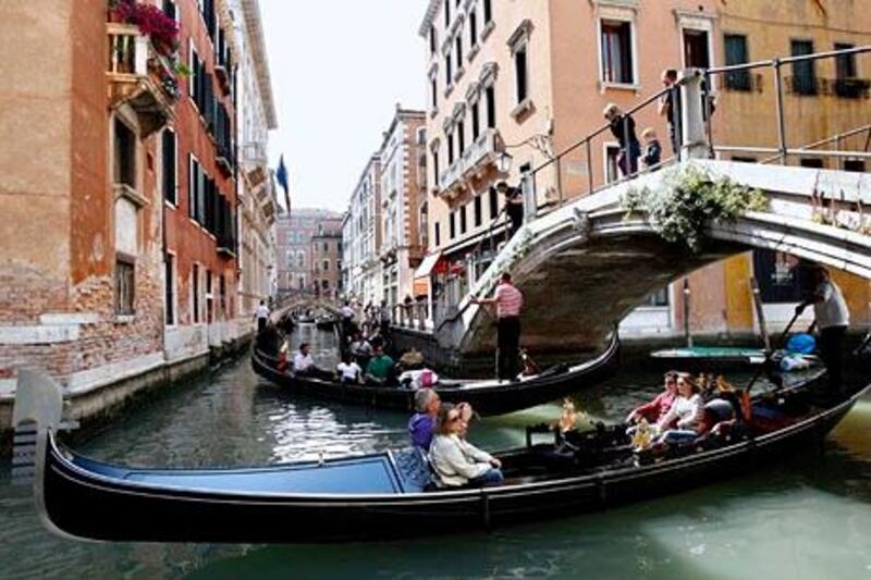 Gondoliers row gondolas with tourists in a canal in Venice in this May 7, 2011 file photo. Italy's leading heritage group on July 4, 2011 urged the United Nations should put Venice on its danger list, saying mass tourism, environmental neglect and urban sprawl were sounding the lagoon citys death knell. REUTERS/Stefano Rellandini/Files   (ITALY - Tags: TRAVEL ENVIRONMENT) *** Local Caption ***  ROM301_ITALY-VENICE_0704_11.JPG