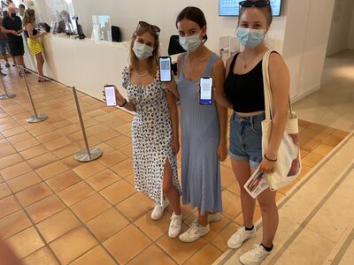 Lena Haeberli, Celine Lorenz and Leonie Gohl, on holiday in the south of France from Zurich, show their mobile phones with proof of double vaccination at the Matisse museum in Nice. Colin Randall/The National