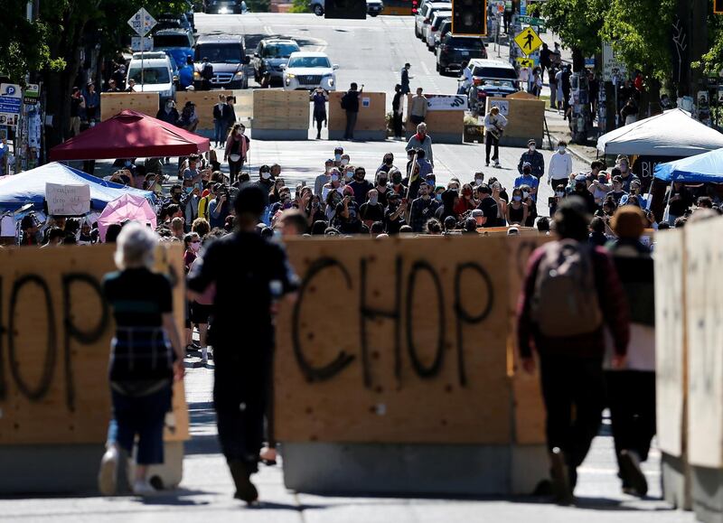 People walk between concrete barriers newly installed by the city as protesters demonstrate against racial inequality and occupy space at the CHOP area near the Seattle Police Department's East Precinct in Seattle, Washington, U.S. REUTERS