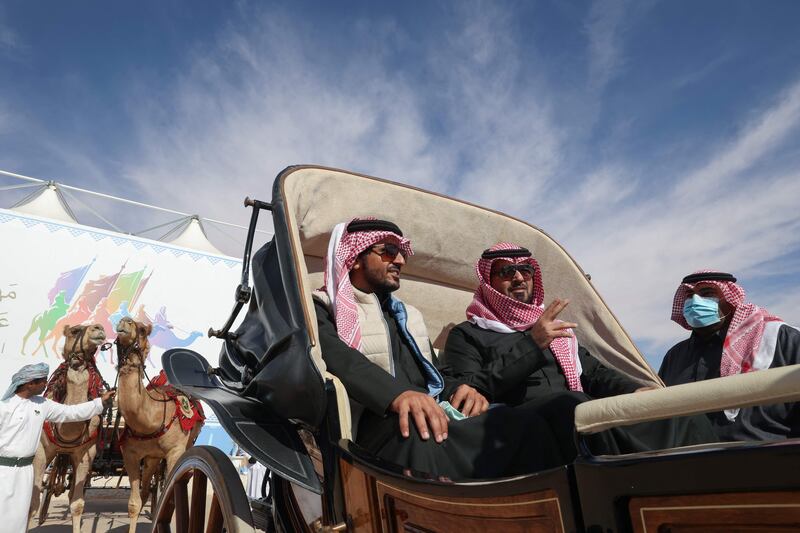 Emirati men ride in a camel carriage at the festival.