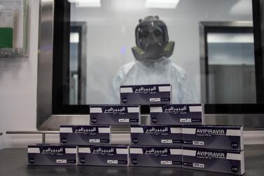 An Eva Pharma employee with a face mask behind boxes of the antiviral medication Favipiravir at the company's Cairo base.  The company also secured a licence from  Gilead Sciences earlier this month to make Remdesivir in Egypt and distribute it in 127 countries. EPA