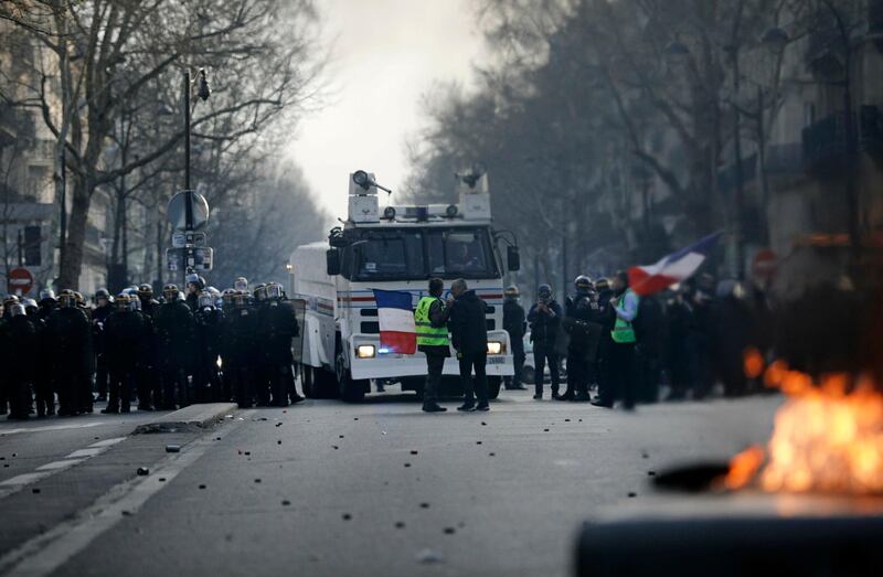 Demonstrators face police officers during minor clashes with police in Paris, Saturday, March 23, 2019. The French government vowed to strengthen security as yellow vest protesters stage a 19th round of demonstrations, in an effort to avoid a repeat of last week's riots in Paris. (AP Photo/Kamil Zihnioglu)