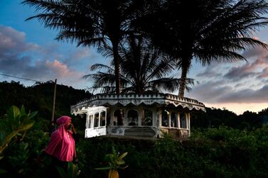 A woman walks past a mosque minaret devastated on 2004 by an earthquake and tsunami called 'Boxing Day Tsunami', in Lhokseudu, Aceh province on December 24, 2019. AFP