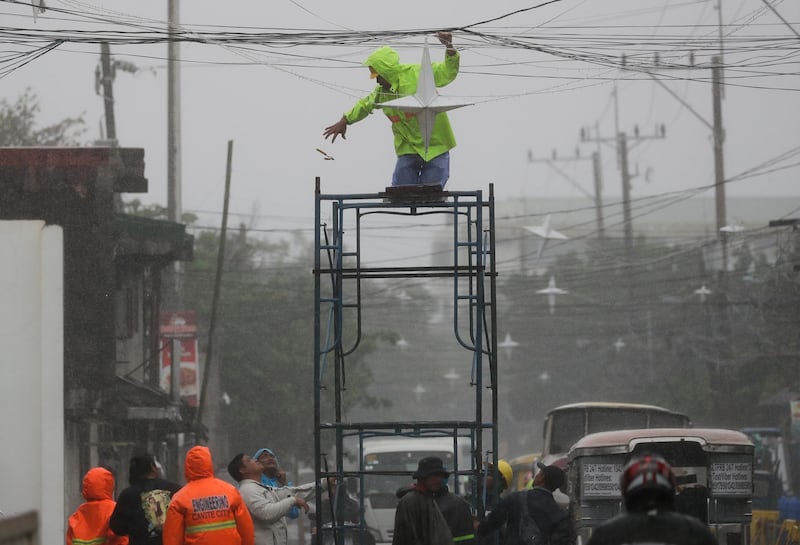 A man prepares to take down Christmas lanterns ahead of approaching Typhoon Kammuri. AP Photo