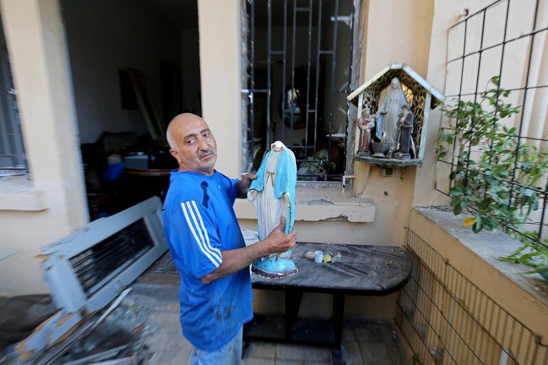 A man holds a damaged sculpture depicting Mary in his house near the site of Tuesday's blast in Beirut's port area. Reuters
