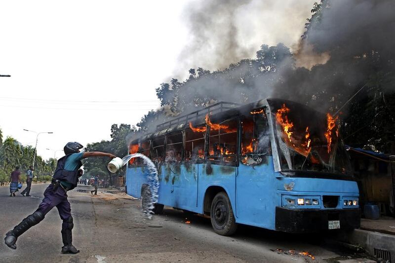 A Bangladesh police officer throws water at a bus set alight during a protest ahead of a three-day strike n the capital Dhaka on November 3, 2013.  The chief opposition Bangladesh Nationalist Party called for the strike ahead of the January 2014 parliamentary elections. AFP photo