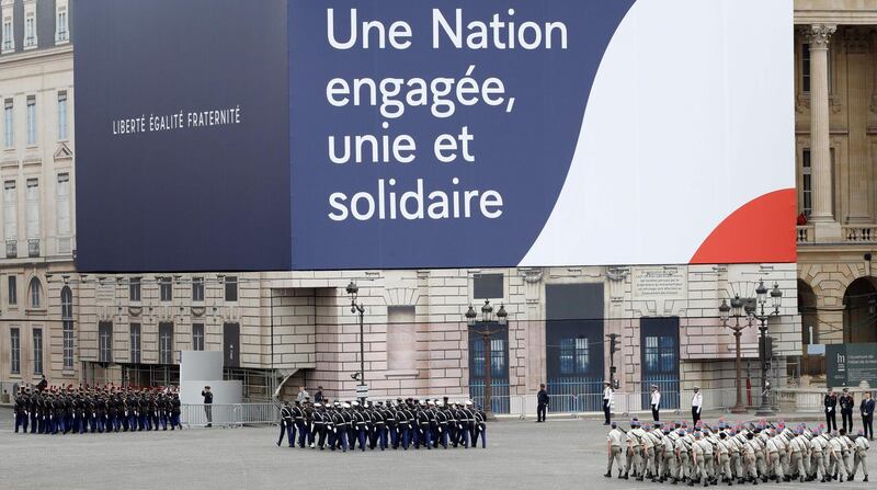 French troops march by a banner reading 'a committed, joint and united nation' during in the annual Bastille Day ceremony. AFP