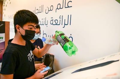 Rowena Mercado, and her son Jaydean Mercado, 14 use the Cycle machine for the first time to recycle the plastic bottles at World Trade Centre Mall, Abu Dhabi. Khushnum Bhandari / The National
