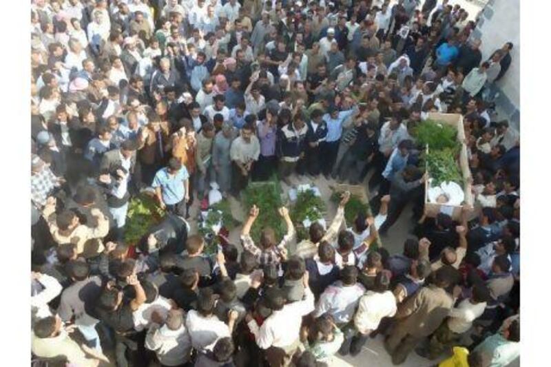 Anti-government protesters attend the funeral of Sunni Muslim villagers killed on Wednesday near Homs. Syrian activists said that security forces shot dead at least 11 villagers at a roadblock near Homs.