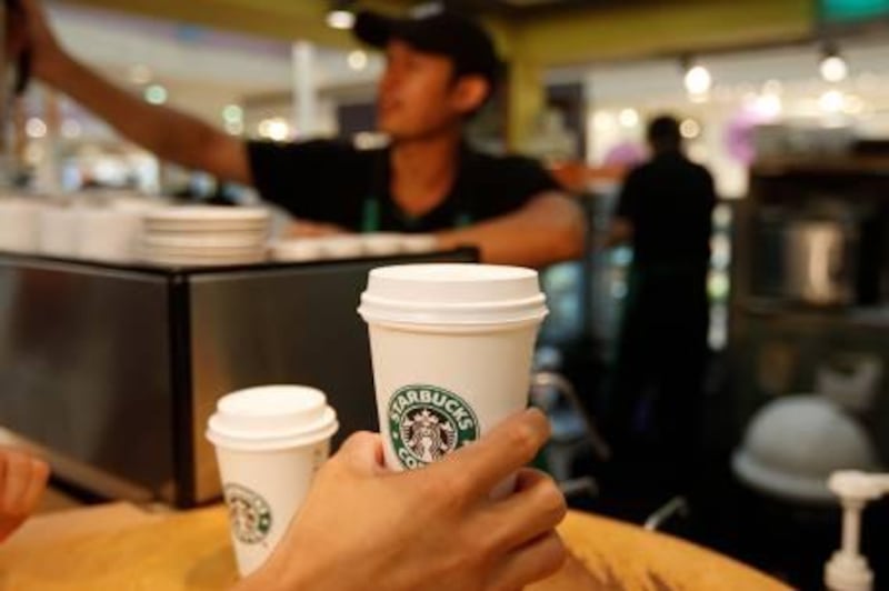 ABU DHABI, UNITED ARAB EMIRATES - July 16, 2008: A customer picks up his coffee at Starbucks in Marina Mall in Abu Dhabi. ( Ryan Carter / The National ) *** Local Caption ***  RC003-Starbucks.JPGRC003-Starbucks.JPG