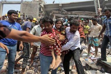 Rescuers assist an injured woman after an eight-storey building housing several garment factories collapses in Savar, near Dhaka.