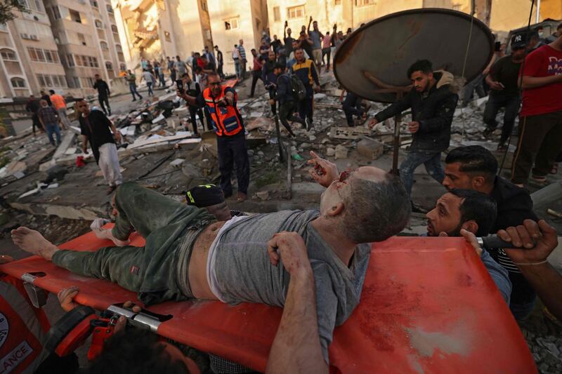 Palestinians carry a survivor from under the rubble of a building, after it was struck by Israeli strikes, in Gaza City. AFP