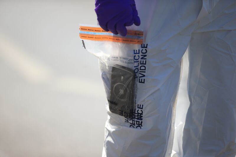 A forensic officer holds an iPhone in an evidence bag. EPA