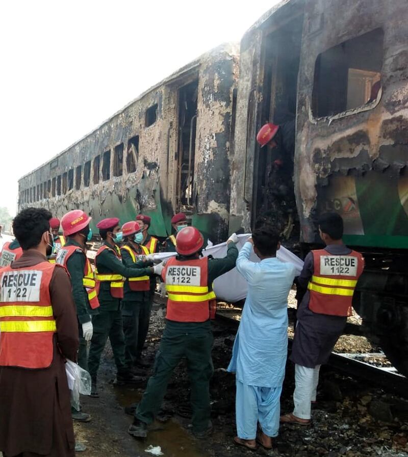 Rescue workers shift the bodies of the victims after a fire engulfed a passenger train near Rahim Yar Khan, Pakistan.  EPA