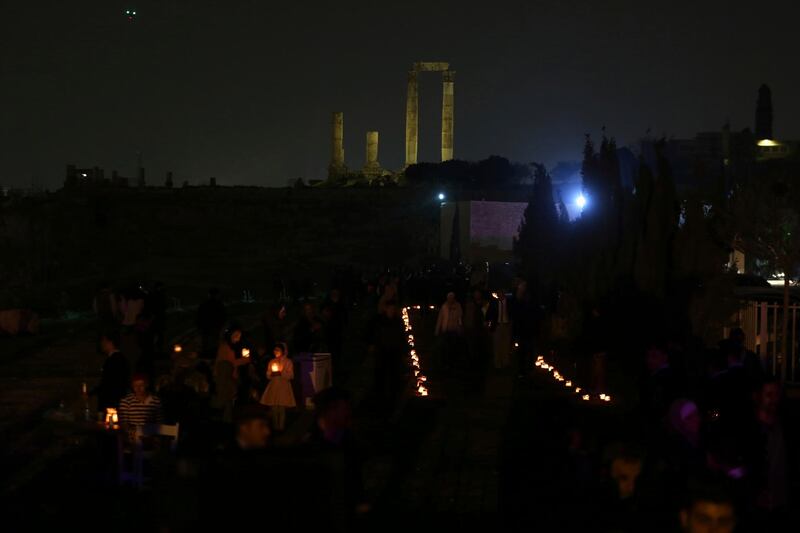 People hold candles as they gather at Amman Citadel to light candles that form the Earth Hour logo, in an official attempt to be registered in the Guinness Book of Records for the largest candle-shaped World Hour logo, in Amman, Jordan. Raad Adayleh / AP Photo
