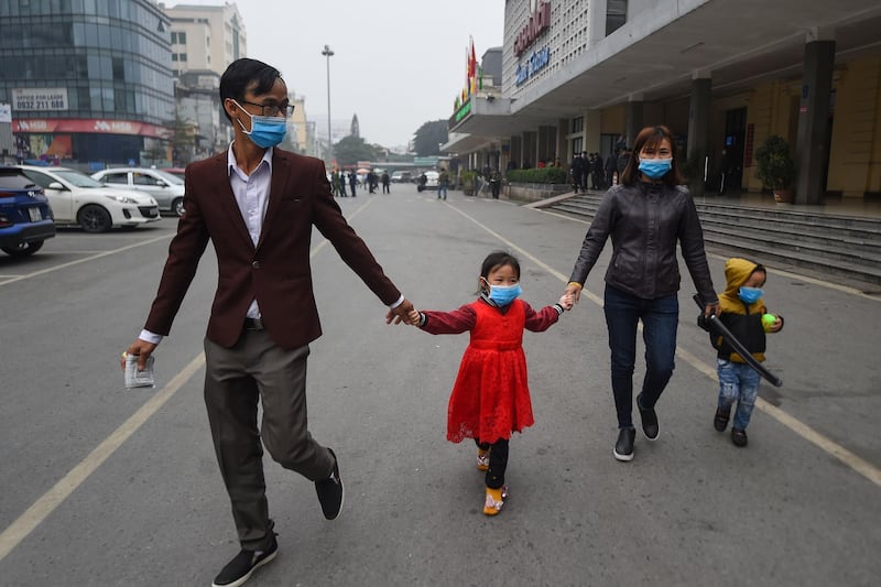 A Vietnamese family wearing protective face masks walk outside a railway station in Hanoi.  AFP