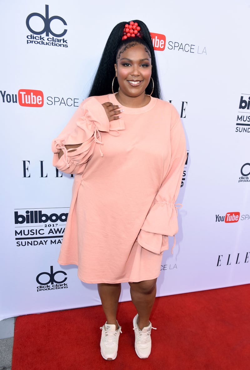 Lizzo wears a loose-fitting blush pink, long-sleeved smock with high ponytail and trainers to the 2017 Billboard Music Awards on May 16, 2017. Getty Images