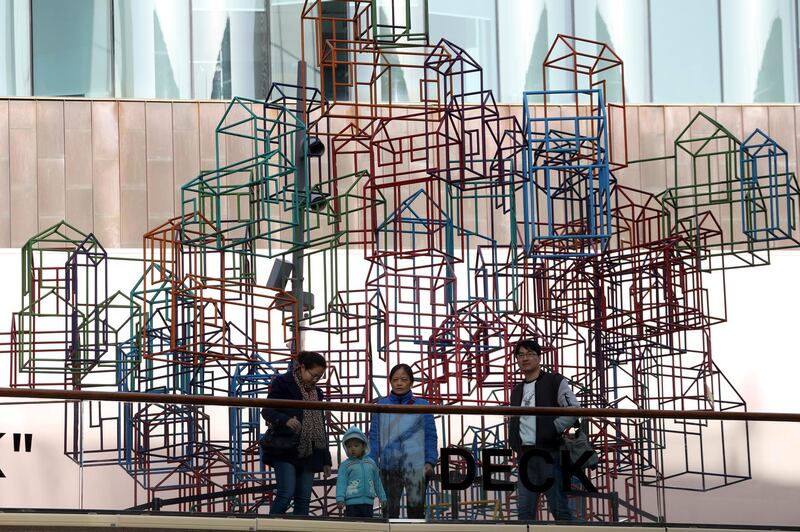 Residents past by a wire frame sculpture resembling houses in Beijing, China, Tuesday, Nov. 27, 2018. Investors have driven up the price of Chinese housing over the past decade, helping to fuel complaints about shortages of affordable living space in Beijing, Shanghai and other big cities. (AP Photo/Ng Han Guan)