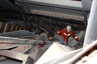 epa08276672 A rescuer follows an injured man walking out of the rubbles of a collapsed five-story hotel building in Quanzhou city in southeast China's Fujian province, 07 March 2020. Over 70 people, mostly people in isolation as a COVID-19 precaution, are feared trapped in the rubbles of the collapsed hotel.  EPA/XIAO FAN CHINA OUT