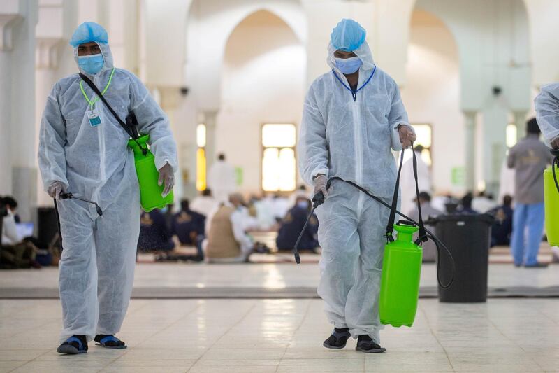 Health workers wearing personal protective equipment disinfect the floor inside the mosque. REUTERS